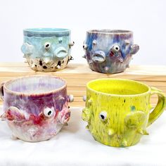 four different colored mugs with faces on them