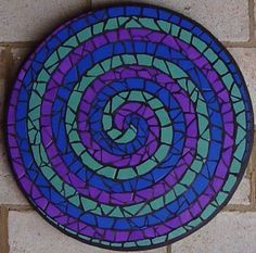 a blue and purple circular design on a brick wall next to a white tile floor