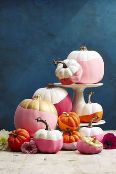 pumpkins and gourds painted in pink, white and orange on a cake stand