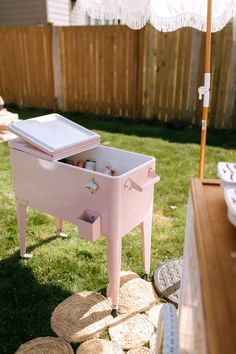 a pink cooler sitting on top of a lush green field