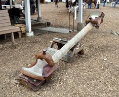 an old wooden bench sitting in the middle of a park filled with lots of people