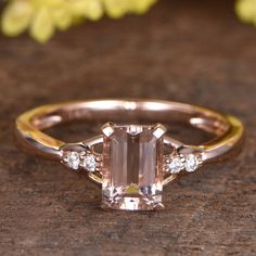 an engagement ring with a green emerald surrounded by three white diamonds on a wooden surface