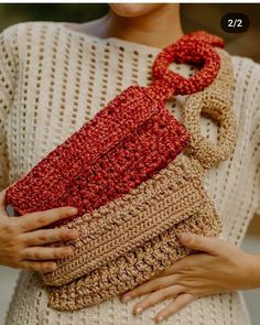 a woman holding a crocheted purse in her hands