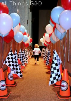 a little boy standing in front of a bunch of balloons and checkered cone cones