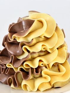 a white plate topped with lots of chocolate and yellow icing next to a fork