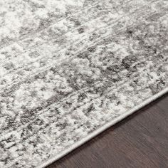 a gray and white rug on top of a wooden floor