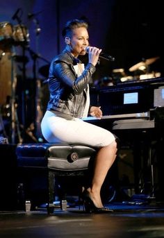 a woman sitting on top of a chair in front of a microphone and piano keyboard