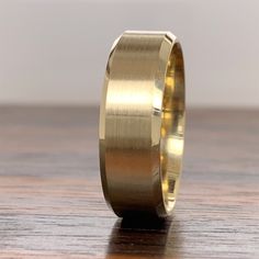 a yellow gold wedding band on top of a wooden table