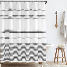 a white shower curtain with black and white stripes on it, next to a bathtub