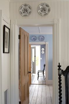 an open door leading to a hallway with plates on the wall and wooden flooring