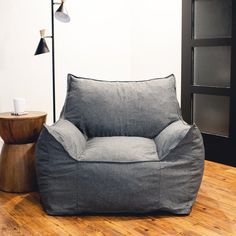 a grey bean bag chair sitting on top of a wooden floor next to a lamp