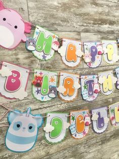 an animal themed birthday banner hanging on a wooden wall next to a stuffed animal toy