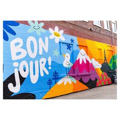 a mural painted on the side of a building that says bon jour with flowers and clouds