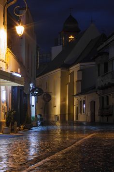 an empty cobblestone street at night with lights on