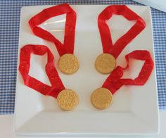 three gold medals on a white plate with red ribbon