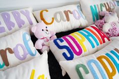 several pillows with colorful letters and teddy bears on them