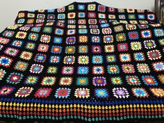 a crocheted granny blanket is displayed on a bed