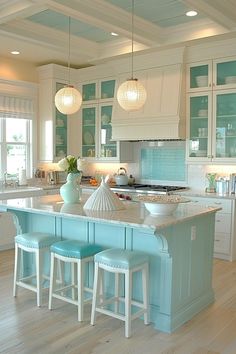 a large kitchen with blue and white decor on the counter tops, island in between two bar stools