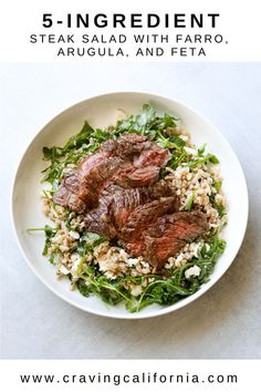 steak salad with faro, arugula and feta on a white plate