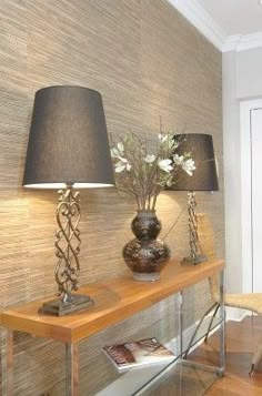 a table with two lamps on top of it next to a wallpapered hallway