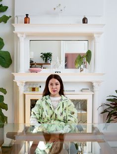 a woman sitting in front of a glass table with a plant on top of it