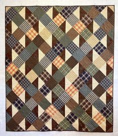 an old quilt hanging on the wall in front of a white wall with a brown and blue checkered pattern