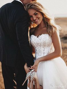 a woman in a white dress is holding onto a man's hand and smiling