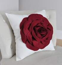 a white pillow with a red rose on it