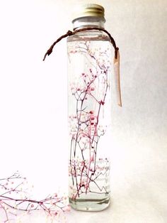 a glass jar filled with flowers on top of a white table next to a string