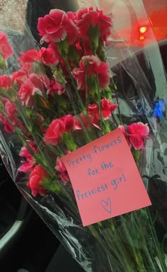 a bunch of flowers that are sitting in the back of a car with a note attached to it