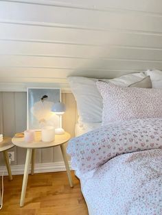 a bedroom with white walls and wood flooring is pictured in this image, there are two nightstands on either side of the bed