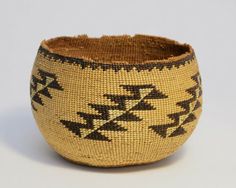 a woven bowl with black and tan designs on it's sides, sitting on a white surface