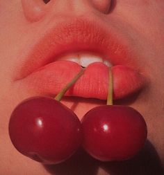 a woman's lips and two cherries sticking out of her mouth