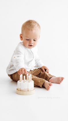 a baby sitting on the floor playing with a wooden block set in front of him