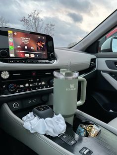 a car dashboard with a cup and cell phone on the dash board next to it