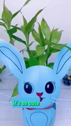 a blue bunny shaped planter sitting on top of a white table next to a potted plant