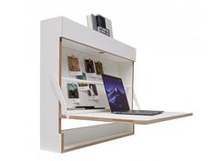 an open laptop computer sitting on top of a white shelf next to a bookshelf