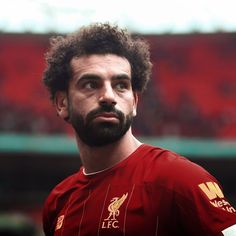 a close up of a soccer player wearing a red uniform and looking at the camera