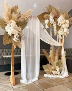 an arrangement of flowers and feathers is on display at a wedding ceremony in front of a white drape