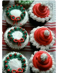 cupcakes decorated with red, green and white frosting are arranged on a table