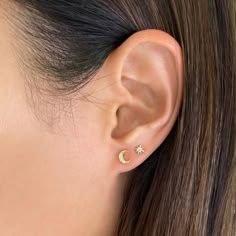 a woman's ear with a small gold star and moon stud in the middle