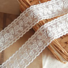 two white laces sitting next to each other on top of a wooden basket in front of a wicker basket