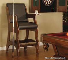 a living room with a pool table, chair and darts on the wall behind it