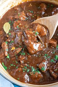 a pot filled with meat and gravy on top of a blue table cloth