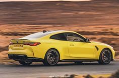 the rear end of a yellow sports car driving on a road in the middle of nowhere