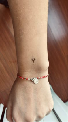 a woman's foot with a small star tattoo on her left ankle and red beaded bracelet