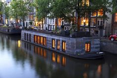 a houseboat is parked on the side of a river in front of some buildings