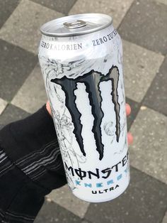 a person holding up a can of monster energy