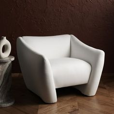 a white chair sitting on top of a hard wood floor next to a marble vase