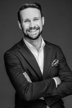 a man in a suit and tie posing for a black and white photo with his arms crossed